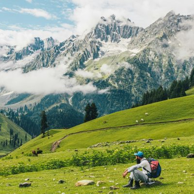person riding motorcycle on green grass field near snow covered mountain during daytime